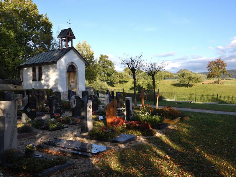 Bild vom Teil des Friedhofs mit einem weiten Ausblick, Gräbern und der Kapelle