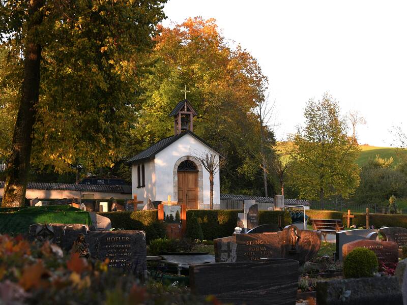 Bild vom Teil des Friedhofs mit Gräbern im Vordergrund und der Kapelle im Hintergrund